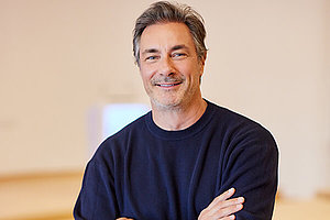 Marco Schreyl Porträt eines Mannes, wahrscheinlich um die 50 Jahre alt, mit kürzeren dunklen Haaren, blauer Pulli, schaut freundlich in die Kamera.