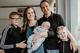 Familienfoto in der Küche: Mutter, Vater, zwei Jungen im Grundschulalter und ein Baby. 