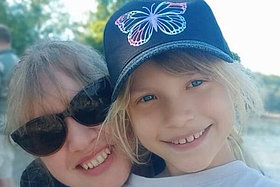 Mandy und ihre Tochter Stelle: eine Frau und ein etwa zehnjähriges Mädchen, beide mit blonden, leicht gelockten Haaren, umarmen sich und schauen lächelnd in die Kamera. Die Frau trägt eine Sonnenbrille, das Mädchen ein blaues Cap.