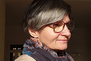 Marion, die Autorin der Kurzgeschichte Porträt einer etwa 50-jährigen Frau, sie schaut zur Seite, hat kürze graumelierte Haare und eine Brille