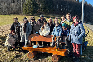 Gruppenbild der Regionalgruppe Fulda des Mukoviszidose e.V. Foto einer Gruppe von Menschen in Winterkleidung vor einer Holzbank auf einer Wiese - im Hintergrund sieht man einen Wald.