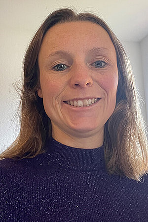 Cora Selfie einer Frau mit dunklen Haaren, wahrscheinlich um die 30 Jahre alt. Sie lacht in die Kamera.