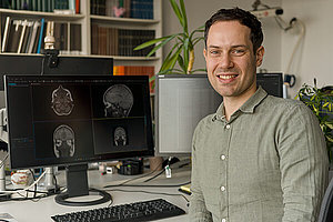 Dr. sc. hum. Niclas Hagen forscht zur KI-gestützten Auswertung von MRT-Aufnahmen Dr. sc. hum. Niclas Hagen sitzt am Schreibtisch vor seinem Computerbildschirm.
