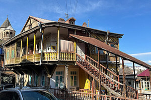 Ein besonders gebautes Holzhaus mit einer umlaufenden Veranda im ersten Stock und einer großen Holztreppe an der Seite. Traditionelle Häuser in Tiflis. 