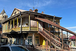 Ein besonders gebautes Holzhaus mit einer umlaufenden Veranda im ersten Stock und einer großen Holztreppe an der Seite. Traditionelle Häuser in Tiflis. 