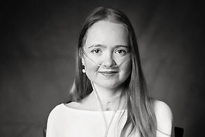 Schwarz-weiß Porträt einer jungen Frau, die ein Sauerstoffgerät mit Nasenbrille trägt. 