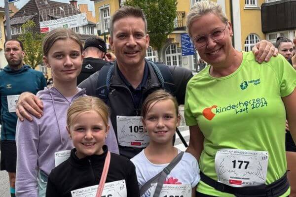 Familie mit drei Töchtern in Laufkleidung posieren lachend vor der Kamera