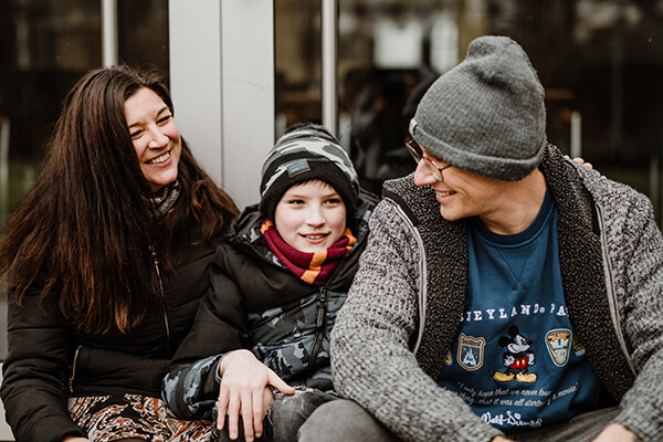 Conner mit seinen Eltern Familienfoto: Mutter, Sohn (11 Jahre) und Vater in Winterkleidung vor einem Fenster