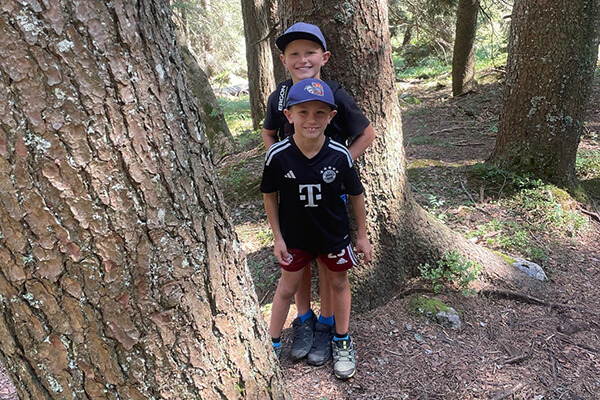 Danielas Söhne Zwei Jungs mit dunklen Fußballtrikots im Wald zwischen Bäumen