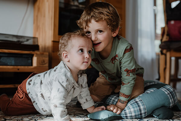 Emil und sein Bruder Anton Zwei kleine Kinder, eines knapp ein Jahr alt, eines vielleicht drei Jahre alt, auf allen Vieren, sie berühren sich am Kopf.